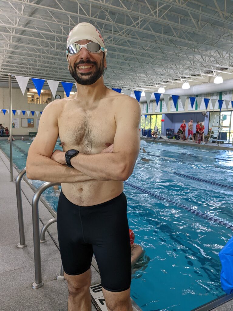 a portrait of the author wearing swimming clothes poolside at a swim meet