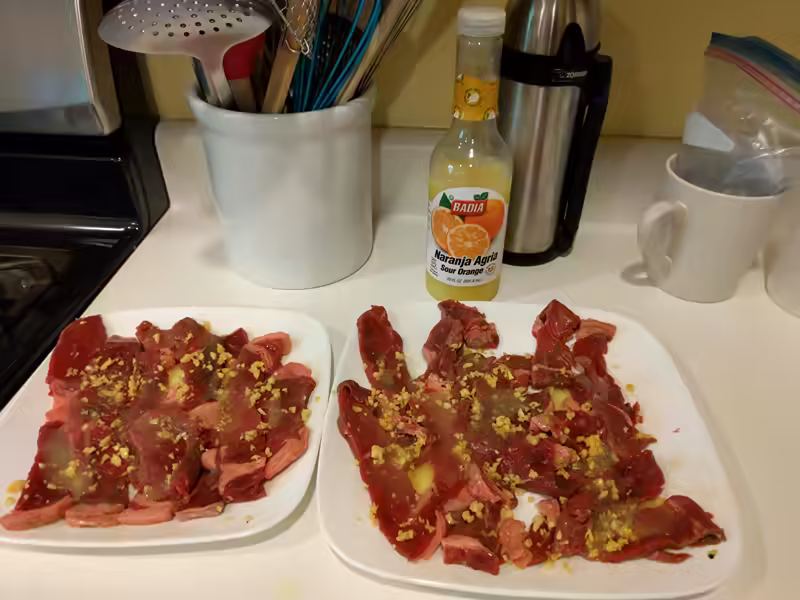 Seasoning the bistec empanizado with naranja agria (sour orange)